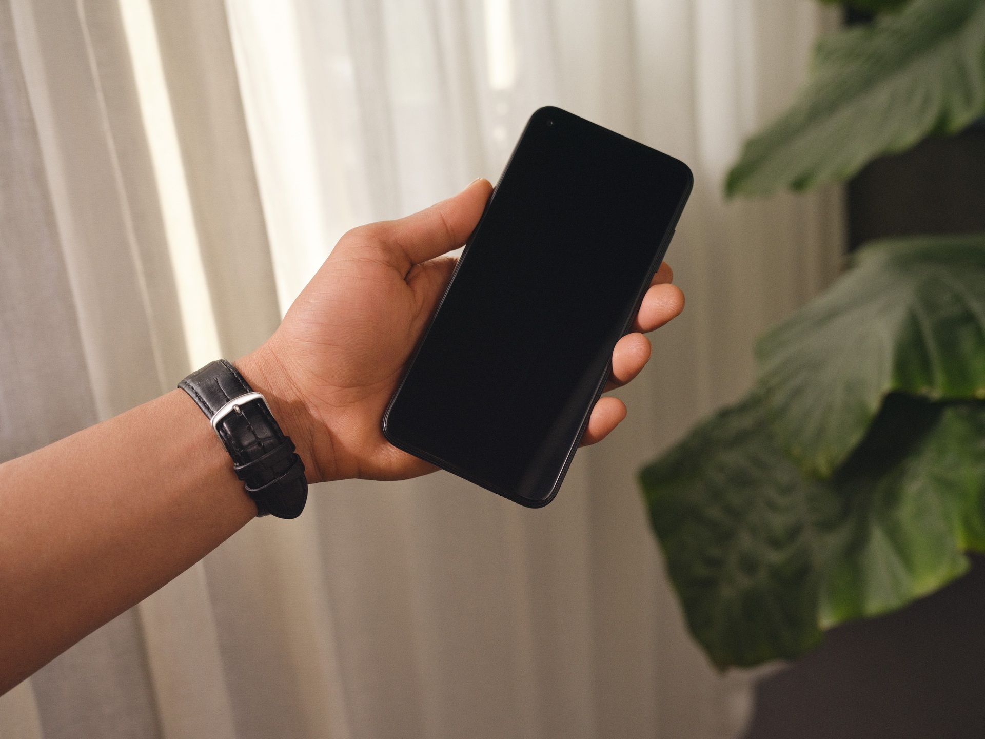 Männerhand hält ein modernes Smartphone mit schwarzem Display