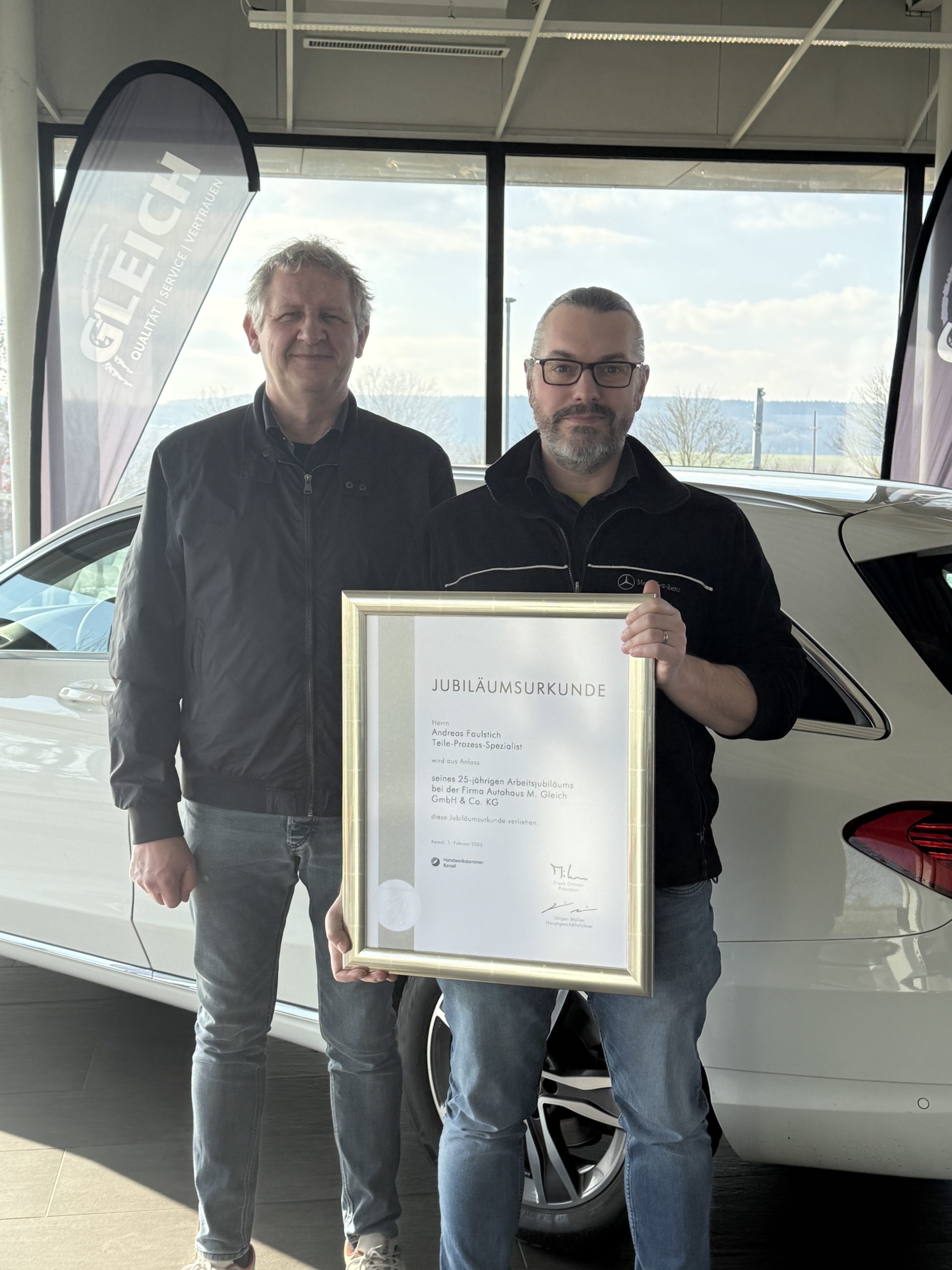 Ein Mann überreicht eine Ehrenurkunde an einen anderen Mann